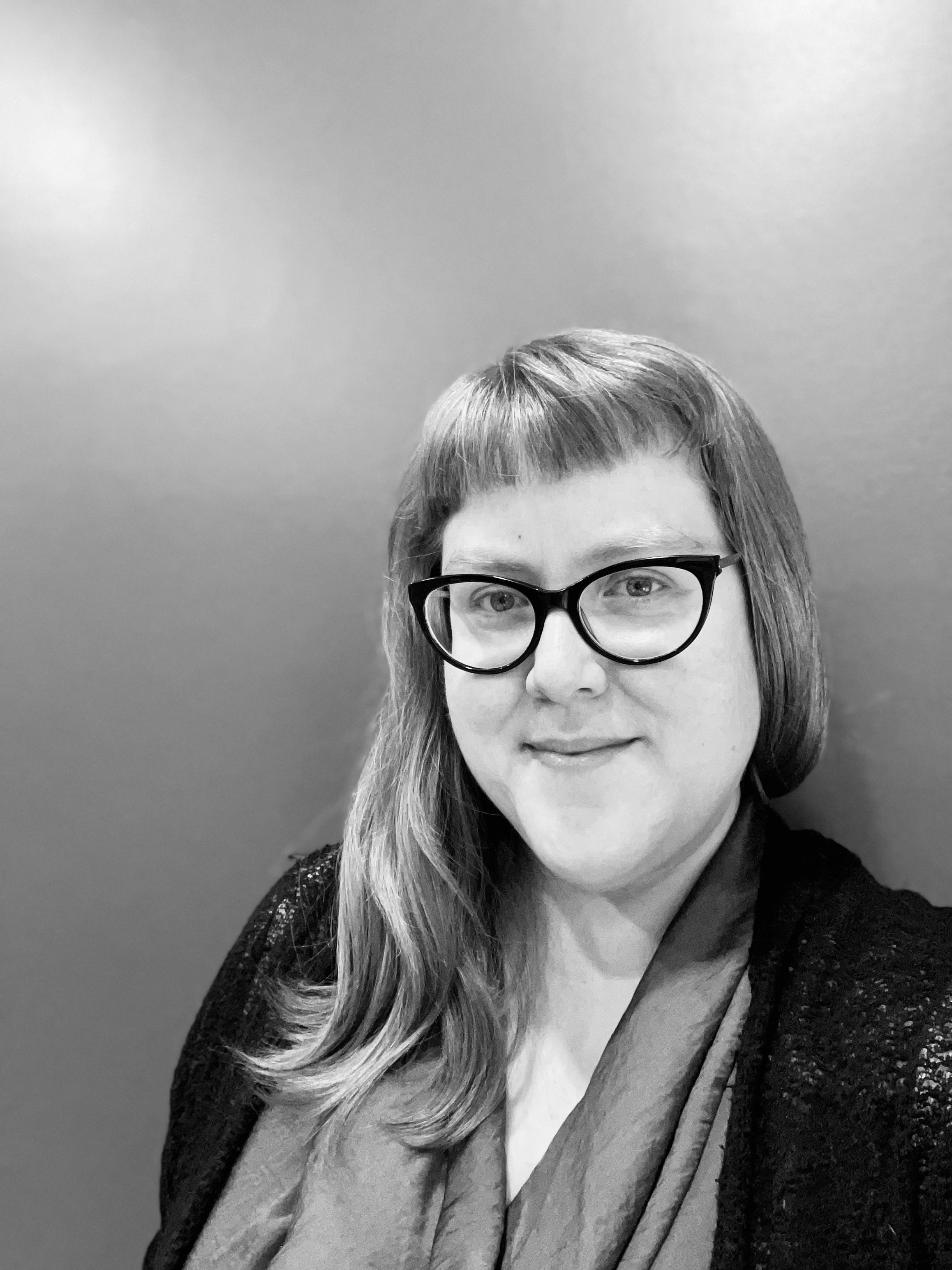 Black and white image of myself, a white woman wearing cat-eye glasses and looking at the camera